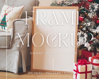 May include: A white frame mockup with a wooden frame, sitting on a wooden floor in front of a Christmas tree decorated with red and green ornaments. The text "FRAME MOCKUP" is written in white on the frame, and the text "SMART OBJECT LAYER" is written below it. The text "JPG FILES + PSD FILES + TUTORIAL" is written below the frame, and the text "EASYEASYMOCKUP" is written below that.