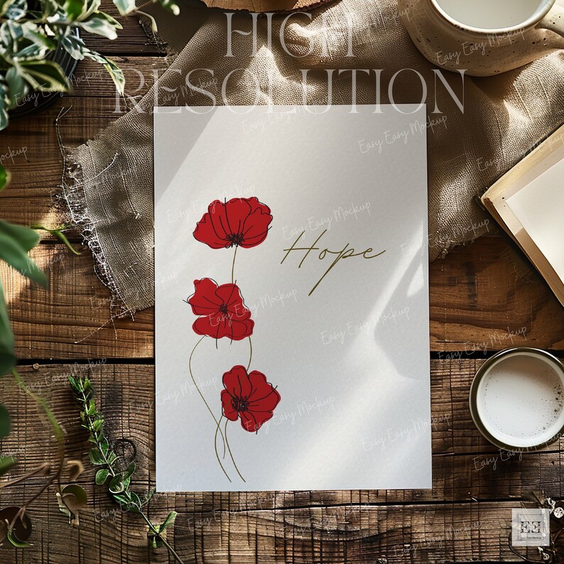 May include: A white card with the word "Hope" written in gold script and three red poppy flowers drawn in black lines. The card is on a wooden table with a cup of coffee and a book.