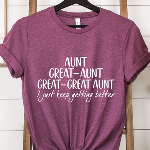 May include: A maroon t-shirt with white text that reads "Aunt Great-Aunt Great-Great Aunt I just keep getting better".