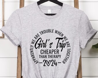 May include: Grey t-shirt with a black circle graphic that says "Apparently we are trouble when we are together. Girl's Trip Cheaper than Therapy -2024- "