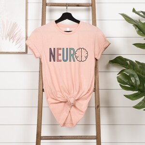 a t - shirt that says neuroo is hanging on a ladder