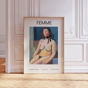 May include: A framed art print featuring a seated nude figure with a black bow. The word "FEMME" is at the top, with event details below. The artwork has a blue, brown, and yellow color palette.