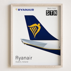May include: A framed print of a Ryanair airplane tail fin with the airline's logo, a yellow harp on a blue background. The text "RYANAIR" is at the top of the print, and "STN" is in a box below the tail fin, with the text "Main Hub" above it. The text "Ryanair" and "Dublin, Ireland" are at the bottom of the print.