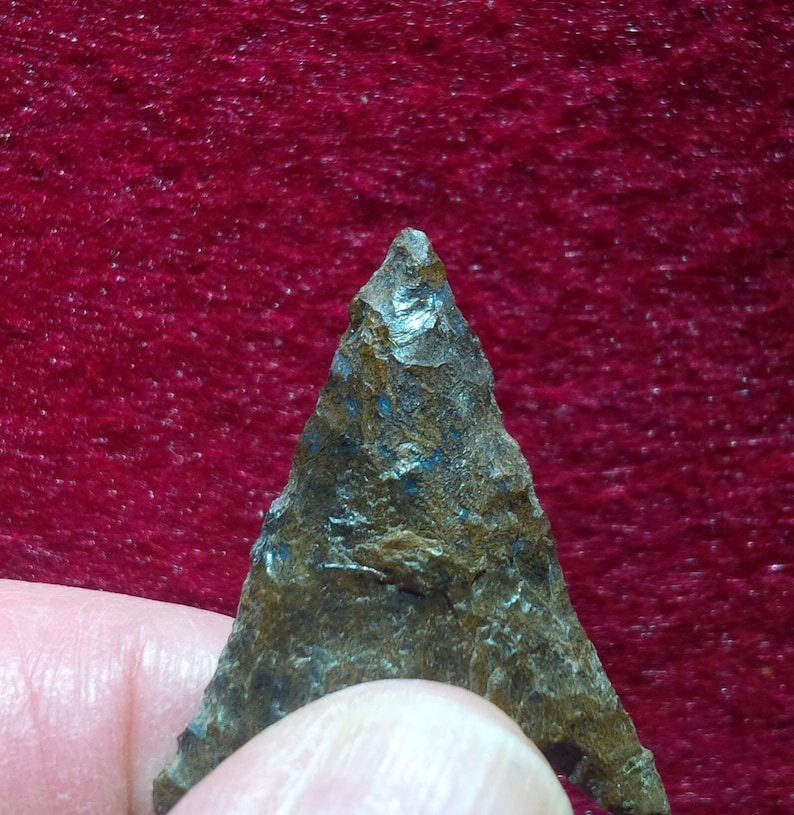 May include: A dark brown arrowhead with a pointed tip and a rough, textured surface.