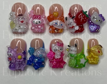 May include: Ten pink and white nail tips with various cartoon characters and designs. The characters include a dog, a cat, a strawberry, a flower, and a star. The designs include a bow, a flower, and a star.