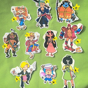 以下が含まれることがあります： 1から10までの番号がついた、カラフルな漫画のキャラクターのステッカーが10枚。ステッカーには、髪型、服装、アクセサリーが異なるキャラクターが描かれています。ステッカーは緑色の背景に貼られています。