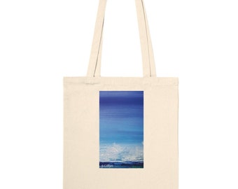 Puede incluir: Una bolsa de lona con una pintura abstracta azul y blanca de un paisaje marítimo. La pintura es de un horizonte con un cielo azul y nubes blancas. La bolsa es de color lona natural.
