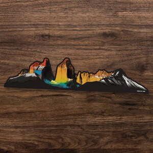 K&ouml;nnte beinhalten: Eine farbenfrohe Illustration der Torres del Paine Bergkette in Patagonien, Chile. Die Berge sind in Orange-, Gelb- und Blaut&ouml;nen dargestellt, mit schneebedeckten Gipfeln. Der Text "Torres del Paine" ist am unteren Rand des Bildes gedruckt.