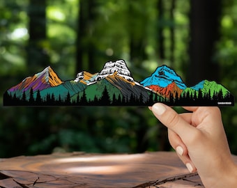 以下が含まれることがあります： 黒い背景に山脈が描かれたカラフルなステッカー。右下に「Canadian Rockies」の文字があります。