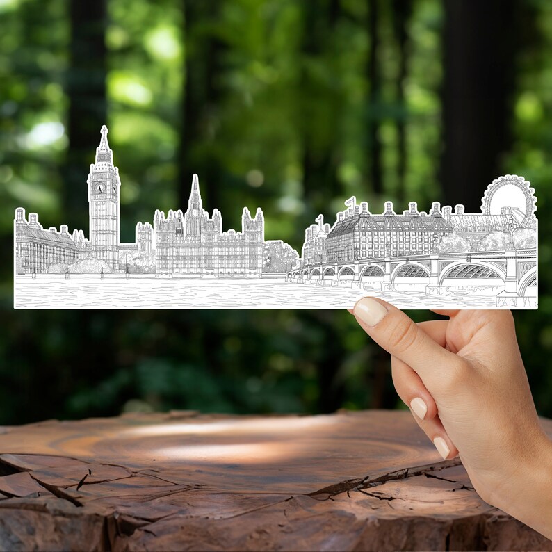 K&ouml;nnte beinhalten: Eine Schwarzwei&szlig;-Zeichnung der Londoner Skyline mit Big Ben, dem Houses of Parliament und dem London Eye. Die Zeichnung wird in einer Hand vor einem verschwommenen gr&uuml;nen Hintergrund gehalten.
