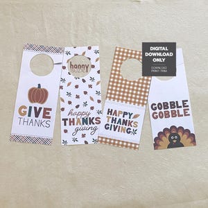 May include: Four printable Thanksgiving door hangers with different designs. The first features a pumpkin and the text "Give Thanks". The second has a fall leaf pattern and the text "Happy Thanks Giving". The third has a gingham pattern and the text "Happy Thanks Giving". The fourth has a turkey and the text "Gobble Gobble".