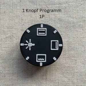 May include: A black, circular control knob with white icons and the text "1 Knopf Programm 1P". The icons include a lightbulb, a rectangle, a wavy line, and a rectangle with a line.