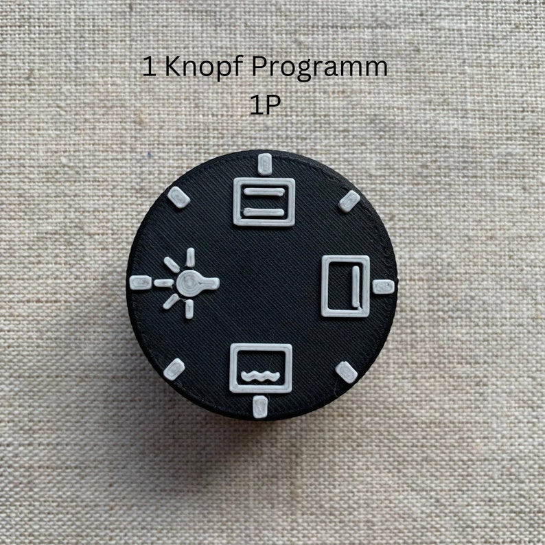 May include: A black, circular control knob with white icons and the text "1 Knopf Programm 1P". The icons include a lightbulb, a rectangle, a wavy line, and a rectangle with a line.