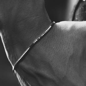 Może przedstawiać: Zbliżenie na nadgarstek z cienkim srebrnym łańcuszkiem.