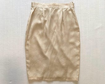 May include: A beige pencil skirt with a textured pattern. The skirt is knee-length and has a tailored fit. The fabric has a subtle sheen, and the skirt appears to be made of a lightweight material. The skirt is suitable for various occasions.