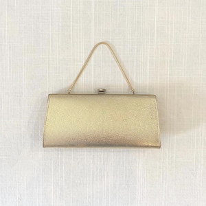 May include: A rectangular gold clutch bag with a metallic textured finish. The bag features a slim, triangular gold metal handle attached to the top frame and a small, centered metal clasp closure for securing the main compartment shut.