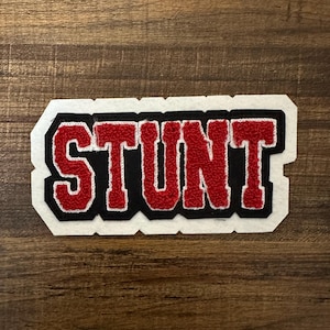 May include: Red and black felt patch with the word "STUNT" in white outlined letters.