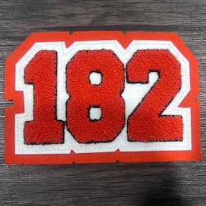 May include: Red felt patch with white stitching and the number 182 in white outlined in black.