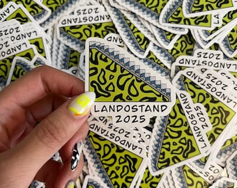 May include: A sticker with the text "LANDOSTAND 2025" in a white rectangle. The sticker features a green and black abstract design and a staircase illustration. Other stickers with the same design are in the background.