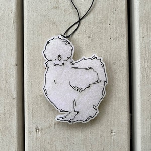 May include: A white, fluffy, chicken-shaped ornament with a black string for hanging.