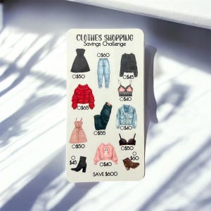 Peut inclure: Une carte rectangulaire blanche avec le texte "CLOTHES SHOPPING Savings Challenge" et des illustrations de vêtements. La carte comprend une robe noire, un jean, une veste rouge, une robe rose et un pull rose. La carte comprend également une paire de bottines noires.