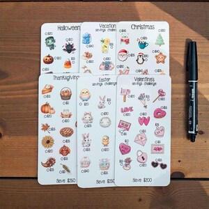 May include: A set of savings challenge cards with themes including Halloween, Vacation, Christmas, Thanksgiving, Easter, and Valentine's. Each card has themed illustrations and savings amounts. A black marker is on the right.