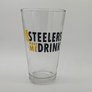 Puede incluir: Un vaso de pinta de vidrio transparente con un gráfico negro y amarillo que dice "Steelers Make Me Drink".