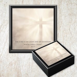 May include: A framed print and a small box, both featuring a cross design with a light emanating from behind. The text "THE LORD IS MY LIGHT AND MY SALVATION; WHOM SHALL I FEAR?" is displayed on both items. The frame and box are black.
