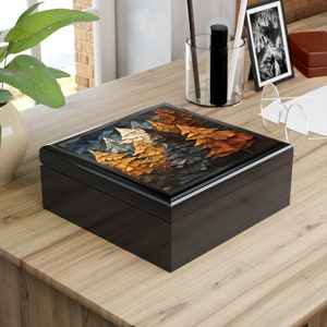 May include: Black wooden box with a hinged lid. The lid features a colorful mosaic design of three trees with brown, orange, and blue tones.