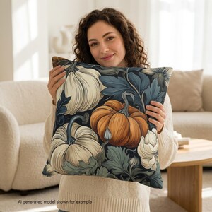 May include: A square throw pillow featuring a dark background with a repeating pattern of orange and cream-colored pumpkins surrounded by dark blue and sage green foliage and leaves. The design covers the entire front surface of the pillow.
