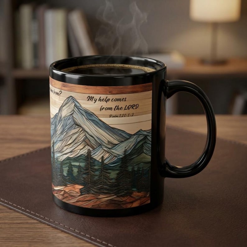 May include: A black ceramic mug featuring a graphic of a mountain range and pine forest with a wood-grain texture background. The text reads, "My help comes from the LORD" and "Psalm 121:1-2". Steam rises from the dark liquid inside the mug.