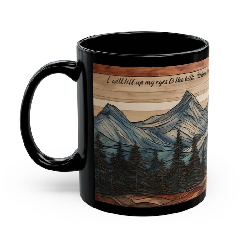May include: A black ceramic mug featuring a wrap-around graphic of a mountain range and pine forest with a wood-grain texture background. The text "I will lift up my eyes to the hills" is printed in black script near the top of the mountain illustration.