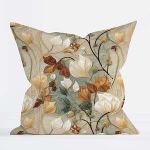 May include: A square throw pillow featuring a botanical pattern with white, cream, and brown leaves and flowers set against a soft sage green background. The design includes delicate, flowing stems and layered foliage with a smooth, matte finish.