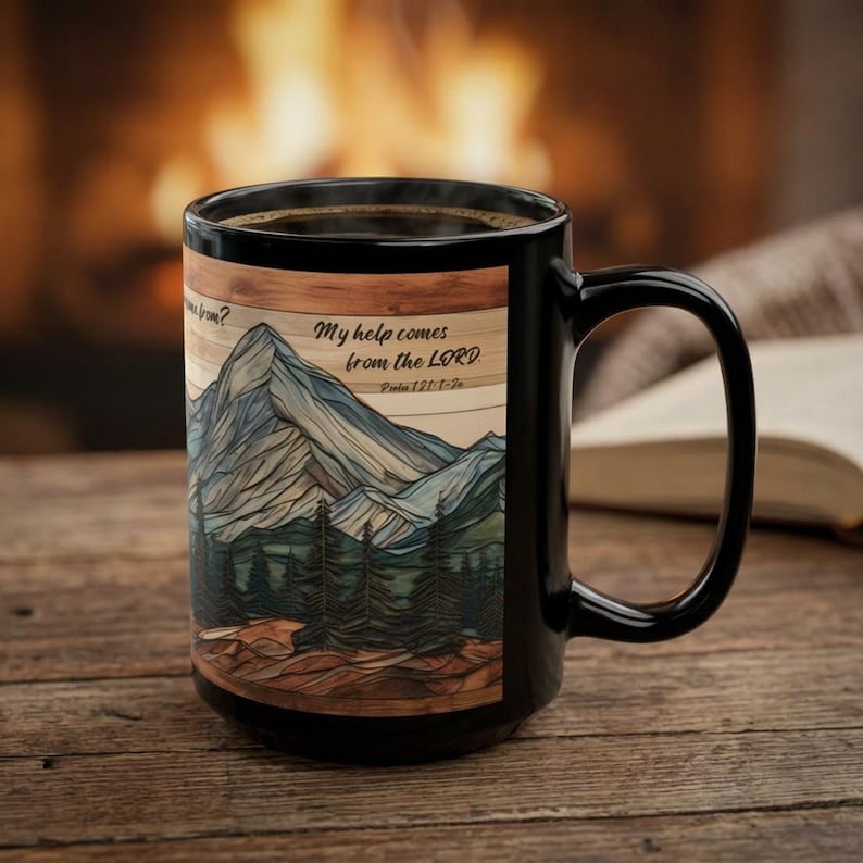 May include: A black ceramic mug featuring a graphic illustration of a mountain range and pine forest. The text reads, My help comes from the LORD. Psalm 121:1-2. The design is set against a wood-grain background with a dark handle.