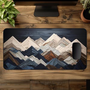 May include: A rectangular mouse pad featuring a mountain range design in shades of blue, brown, and beige. The mountains have a layered, textured appearance. A black computer mouse is on the right side of the pad. The pad is on a wooden desk.