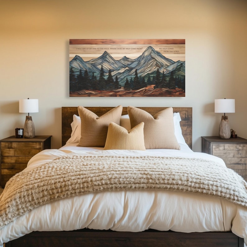 May include: A wooden wall art piece depicting a mountain landscape with pine trees in shades of blue, green, and brown. The artwork hangs above a bed with beige pillows and a textured blanket. The text on the art reads: "I will lift up my eyes to the hills. Where does my help come from? My help comes from the Lord."