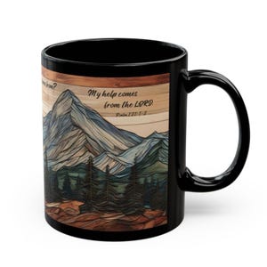 May include: A black ceramic mug featuring a printed graphic of a mountain range and pine forest over a wood-grain background. The text reads: My help comes from the LORD. Psalm 121:1-2. The design wraps around the exterior of the mug.
