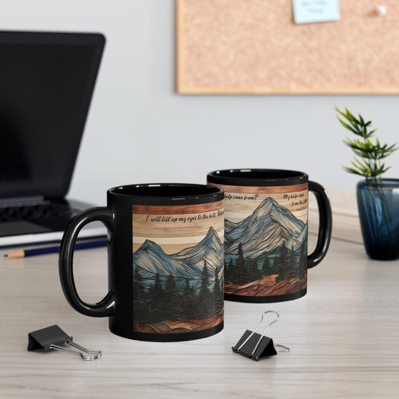 May include: Two black ceramic mugs featuring a wrap-around graphic of a mountain range and pine forest with a wood-grain texture background. The text reads: I will lift up my eyes to the hills. Where does my help come from? My help comes from the LORD.
