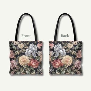 May include: A tote bag with a floral pattern. The front and back of the bag are shown, each with a dark background and a design of colourful flowers, including pink, yellow, and white blooms. The bag has black handles.
