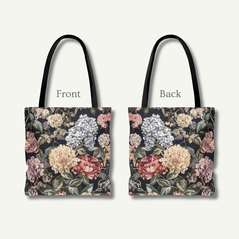 May include: A tote bag with a floral pattern. The front and back of the bag are shown, each with a dark background and a design of colourful flowers, including pink, yellow, and white blooms. The bag has black handles.