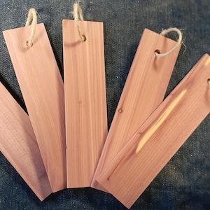 Puede incluir: Cinco tablas de madera de cedro con cuerda atada a cada extremo. Las tablas son de color marrón rojizo claro y tienen una veta de madera natural.