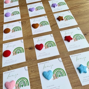 Può includere: Un set di 10 scatole portaconfetti con un design a arcobaleno e un orsacchiotto. Ogni scatola ha un cuore, una stella o un cerchio di colore diverso in carta. Le scatole sono decorate con il testo "Il battesimo di Lorenzo" e la data "02/06/2024".