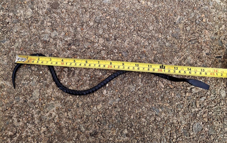K&ouml;nnte beinhalten: Eine schwarze Schlange, die auf einer grauen Betonfl&auml;che 40,6 cm lang ist.