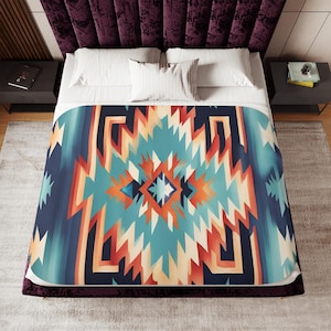 Könnte beinhalten: Eine blaue, orange und weiße geometrisch gemusterte Tagesdecke mit südwestlichem Design.