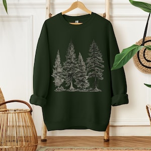 May include: A dark green sweatshirt with a graphic print of a forest scene featuring five trees. The trees are drawn in a simple, minimalist style with gray lines.
