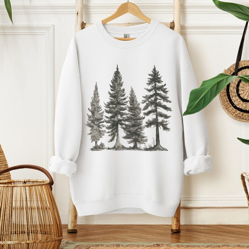 May include: White sweatshirt with a black and white illustration of four pine trees.