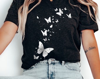 May include: A dark gray t-shirt with a white butterfly design. The butterflies are scattered across the shirt, with a larger butterfly in the center.
