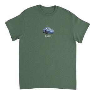 Op de afbeelding: Een groen T-shirt met korte mouwen met een blauwe cartoonauto en het woord "Clairo" erop gedrukt.