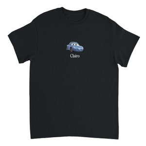 Op de afbeelding: Zwart T-shirt met een blauwe cartoonauto en het woord "Clairo" erop gedrukt.
