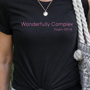 May include: A black t-shirt with the text "Wonderfully Complex" and "Psalm 139:14" in pink lettering.
